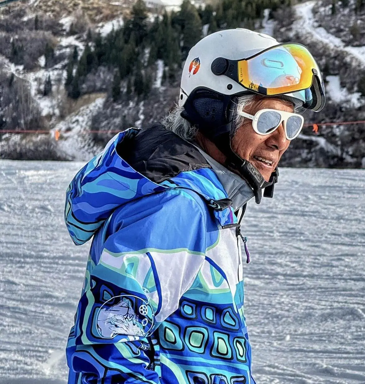 Elderly skier wearing colorful jacket and helmet.